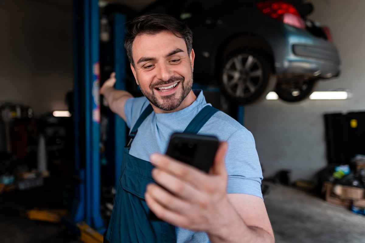 Mechanic smiling and gesturing during a phone call in a garage